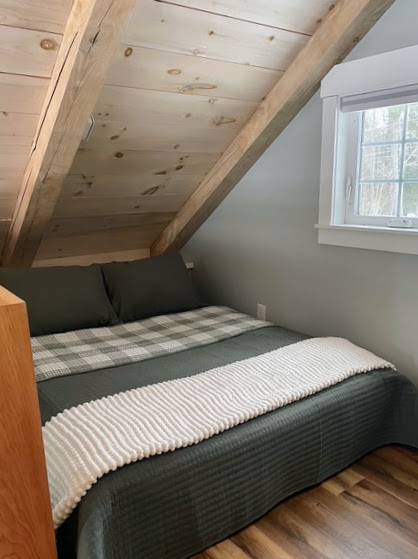 Queen bed in the sleeping loft beneath the pine ceiling