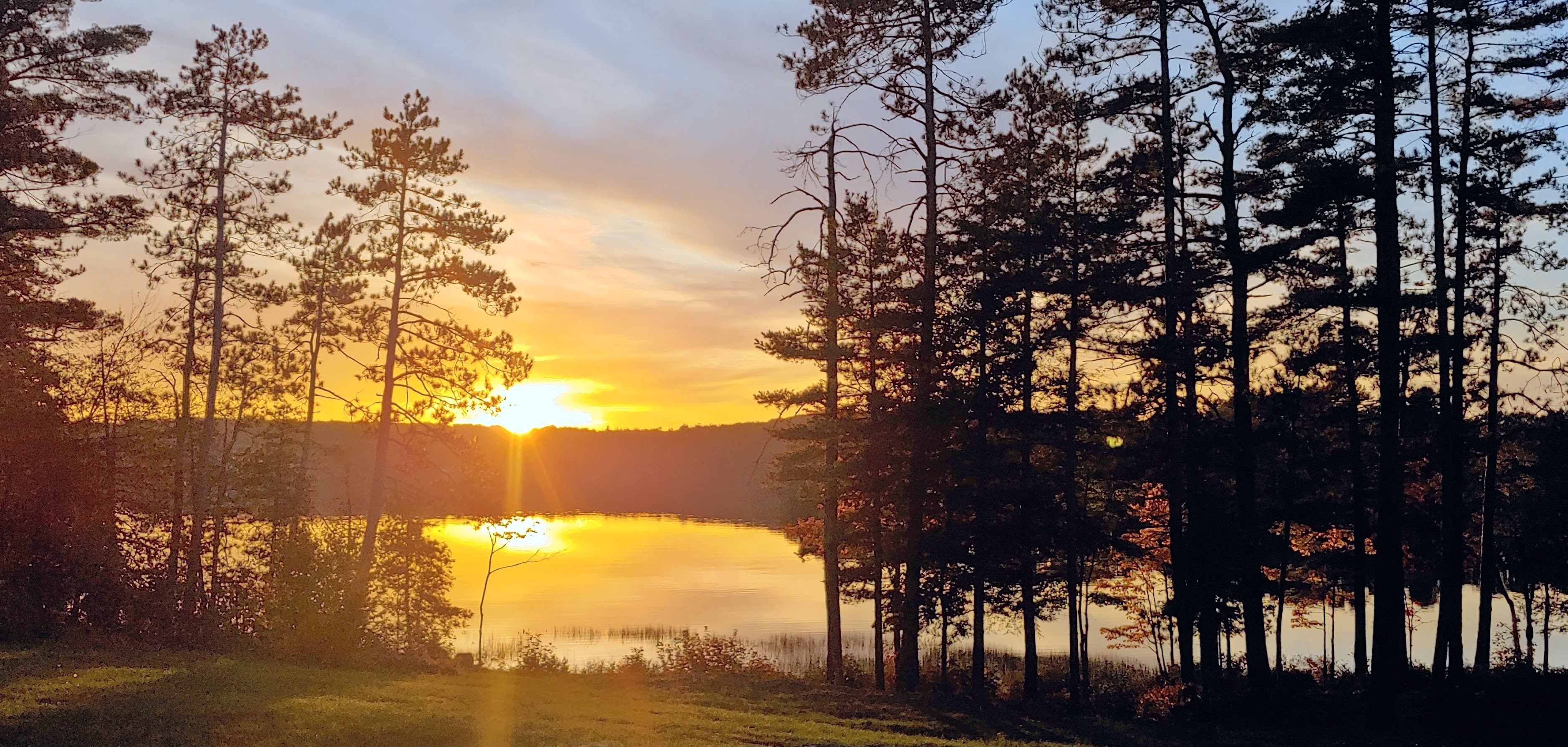 Golden sunset reflected on Pattee Pond from the lawn